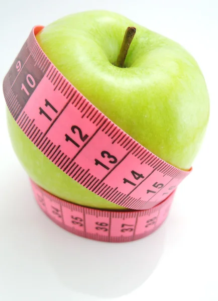 Green apple with pink measuring tape — Stock Photo, Image