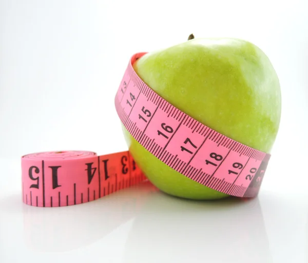 Зеленое яблоко с розовой измерительной лентой изолированы на белой спинке — стоковое фото