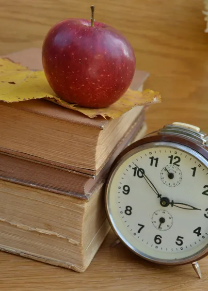 Vintage boeken met oude klok en rode appel — Stockfoto