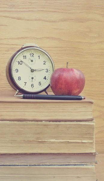 Винтажные часы и яблоко с панцирем на старых книгах — стоковое фото