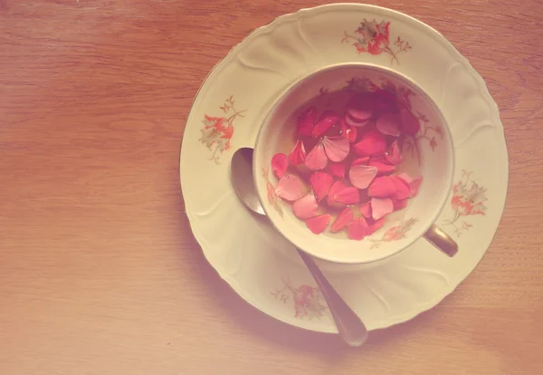 Vintage Tasse Tee mit Blütenblättern auf Holz — Stockfoto