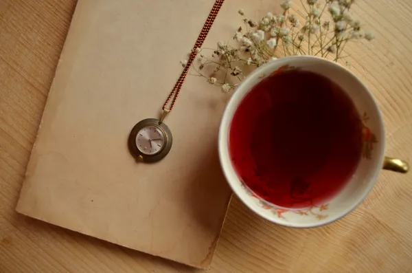 Teetasse, Uhr und altes Buch auf Holzgrund — Stockfoto