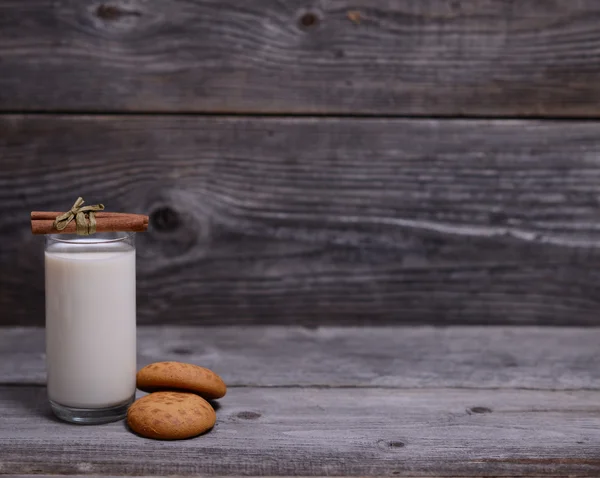 Glass of milk with cinnamon and gingerbread on wooden background — Stock Photo, Image