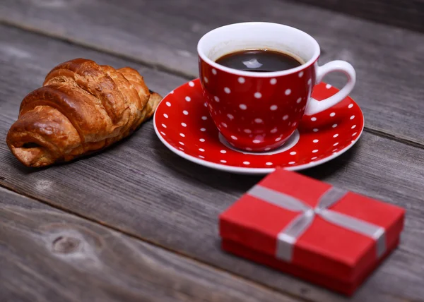 Tasse rouge de café et croissant et petit cadeau — Photo