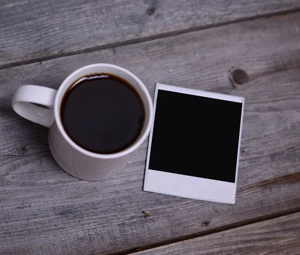 Mug of coffee with photo paper — Stock Photo, Image