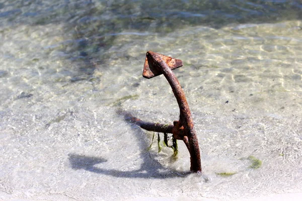 Old rusty boat anchor on the seashore beach during the summer, sunny day