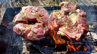 Kömürde pişirilmiş iki parça biftek. Biftek ızgaranın ızgarasında pişiyor.