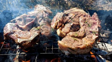 Kömürde pişirilmiş iki parça biftek. Biftek ızgaranın ızgarasında pişiyor.