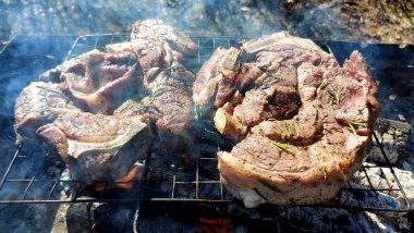 Kömürde pişirilmiş iki parça biftek. Biftek ızgaranın ızgarasında pişiyor.