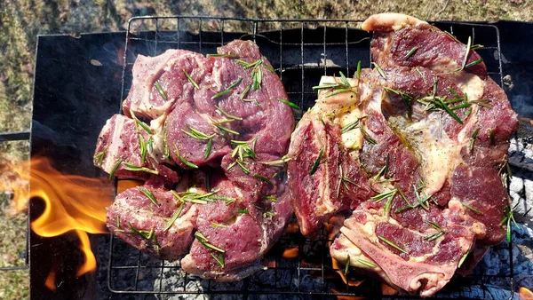 Kömürde pişirilmiş iki parça biftek. Biftek ızgaranın ızgarasında pişiyor.