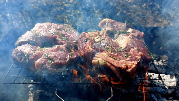 Kömürde pişirilmiş iki parça biftek. Biftek ızgaranın ızgarasında pişiyor.
