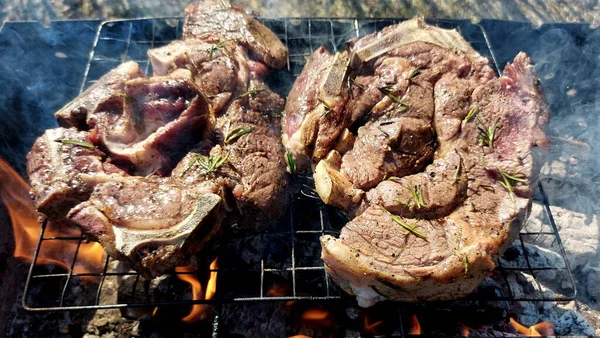 Kömürde pişirilmiş iki parça biftek. Biftek ızgaranın ızgarasında pişiyor.