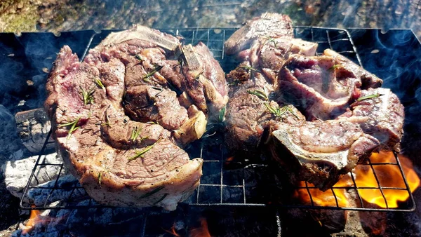 Kömürde pişirilmiş iki parça biftek. Biftek ızgaranın ızgarasında pişiyor.