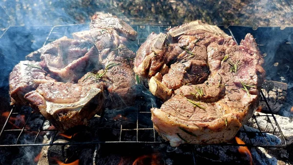 Kömürde pişirilmiş iki parça biftek. Biftek ızgaranın ızgarasında pişiyor.