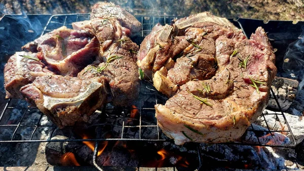Kömürde pişirilmiş iki parça biftek. Biftek ızgaranın ızgarasında pişiyor.
