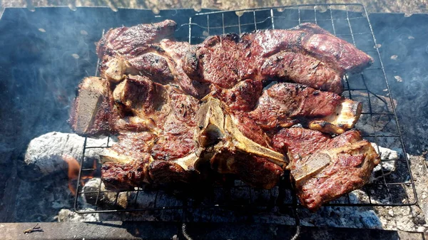 Kömürde pişirilmiş iki parça biftek. Biftek ızgaranın ızgarasında pişiyor.