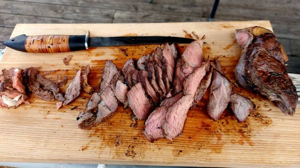 Slices of cut beef steak on a wooden board and steak knife