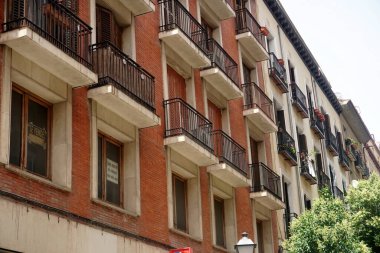   Yazın çeşitli yeşil bitkilerle dolu güzel bir balkona sahip tipik bir İspanyol evinin ön cephesi. Metal parmaklıklı balkon..                            