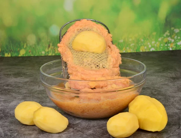 Stock image Potato on a metal potato grater, Grated potatoes