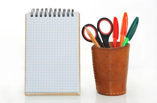 Notebook and a glass with pencils and scissors. — Stock Photo, Image