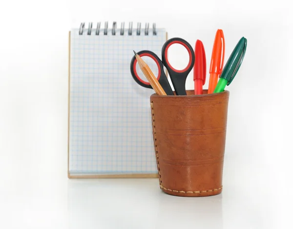 Notebook and a glass with pencils and scissors. — Stock Photo, Image