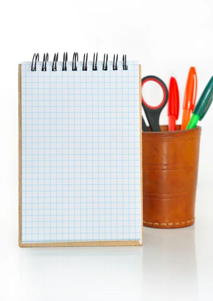 Caderno e um copo com lápis e tesoura . — Fotografia de Stock