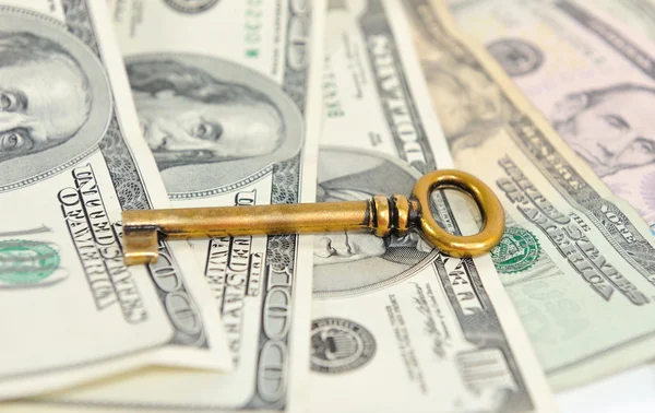 Bronze key from the old furniture in the background of dollar bills. — Stock Photo, Image