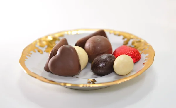 Choklad i olika former på den gyllene tefat. — Stockfoto