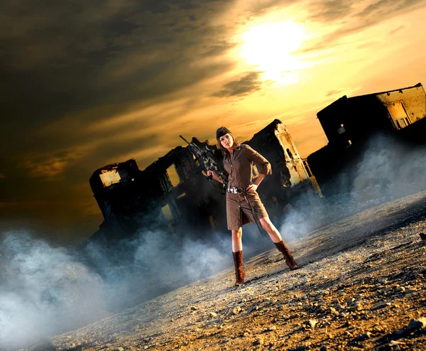 Молода і сексуальна жінка з кулеметом в апокаліптичному пейзажі Стокове Фото