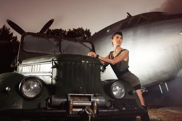 Jovem soldado feminino atraente com o avião e carro — Fotografia de Stock