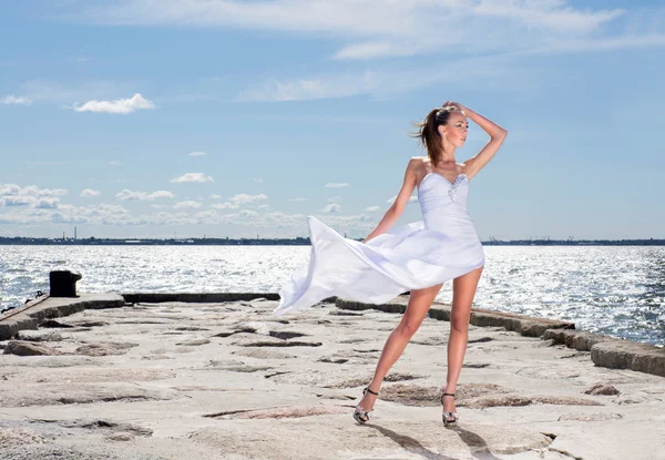 Young sexy girl in a white dress standing on a pier — Stok fotoğraf