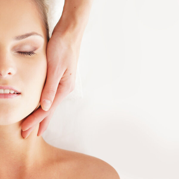 Young attractive woman getting massaging treatment over white ba