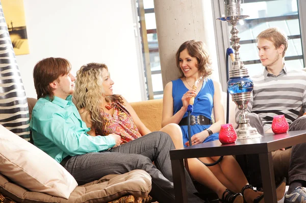 Groupe de jeunes et sexy fumeur narguilé dans le salon caffee Images De Stock Libres De Droits