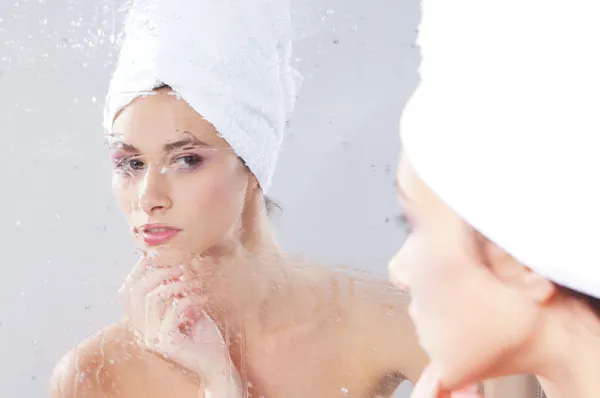 Woman near the mirror in the bathroom. WARNING! THE MIRROR IS WET! NOT ALL THE FACE IS IN FOCUS! — Stock Photo, Image