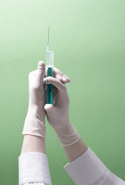 Syringe in handen op groen — Stockfoto