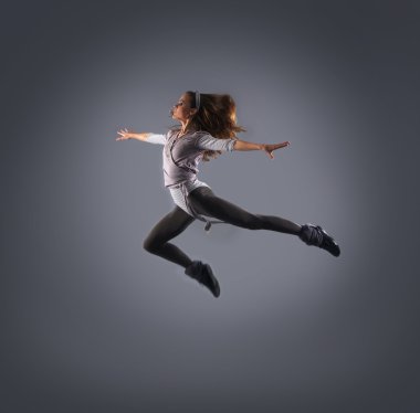 genç, çekici, sportif ve seksi modern dansçı gri arka plan üzerinde atlama