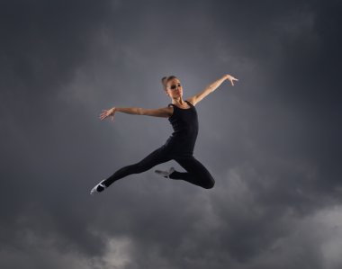 genç, çekici, sportif ve seksi modern dansçı gri arka plan üzerinde atlama