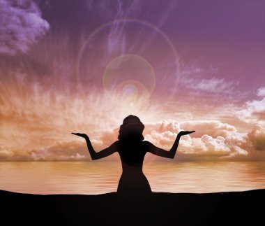 Silhouette of young woman doing yoga exercise over the sunset background