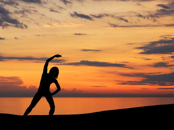 Silhouette of young woman doing exercise over the sunset background — Stock Photo, Image