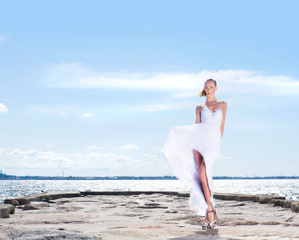 Young sexy girl in a white dress dancing on a pier — Zdjęcie stockowe