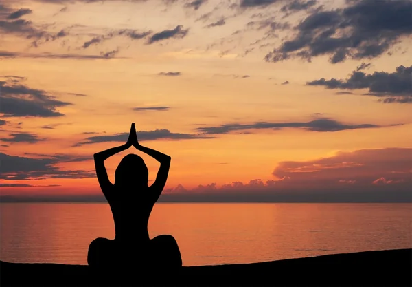 Silhouette de jeune femme faisant de l'exercice de yoga sur le fond du coucher de soleil — Photo