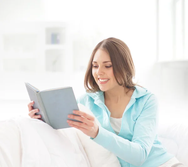 Счастливая женщина сидит в постели и читает книгу — стоковое фото