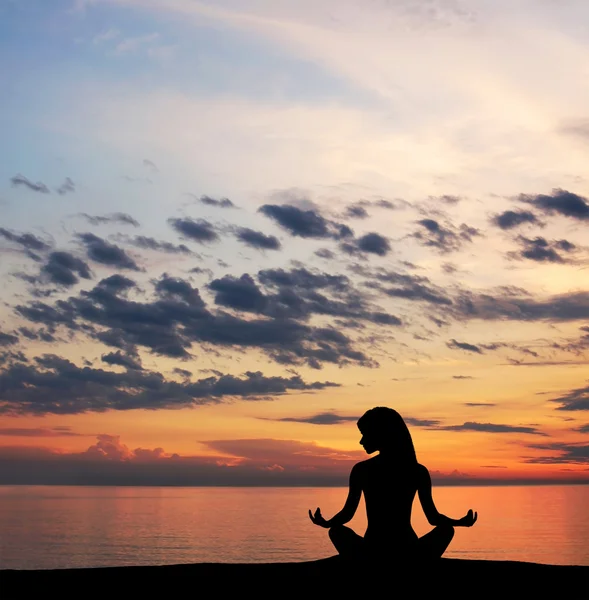 Silhouette of young woman doing yoga exercise over the sunset background — Stock Photo, Image