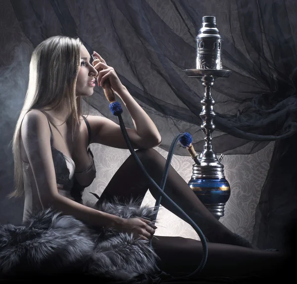 Jovem mulher sexy em roupa interior de luxo fumar o narguilé — Fotografia de Stock