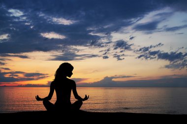 gün batımı ba üzerinde yoga egzersiz yaparak genç bir kadın silueti