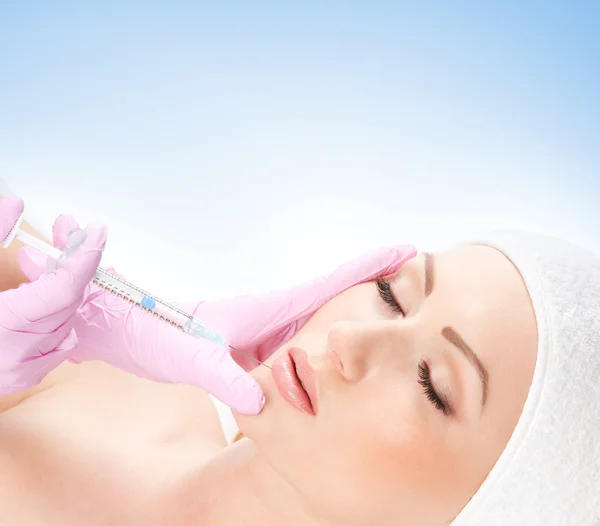 Mulher bonita recebe uma injeção em seu rosto isolado no branco — Fotografia de Stock