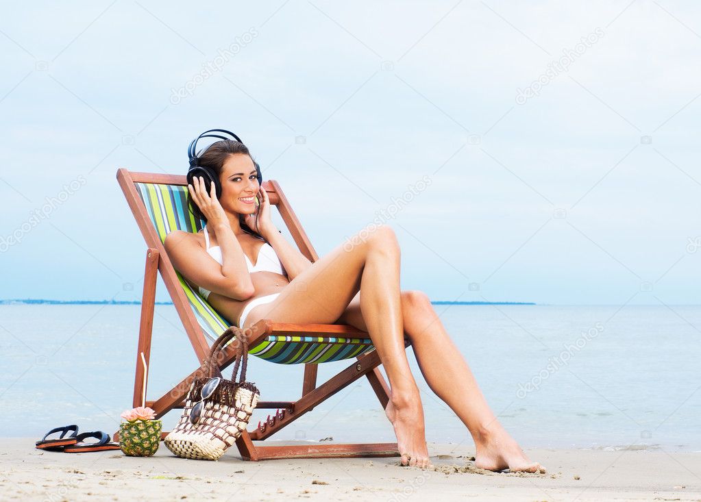 sexy woman listening to the music on the beach