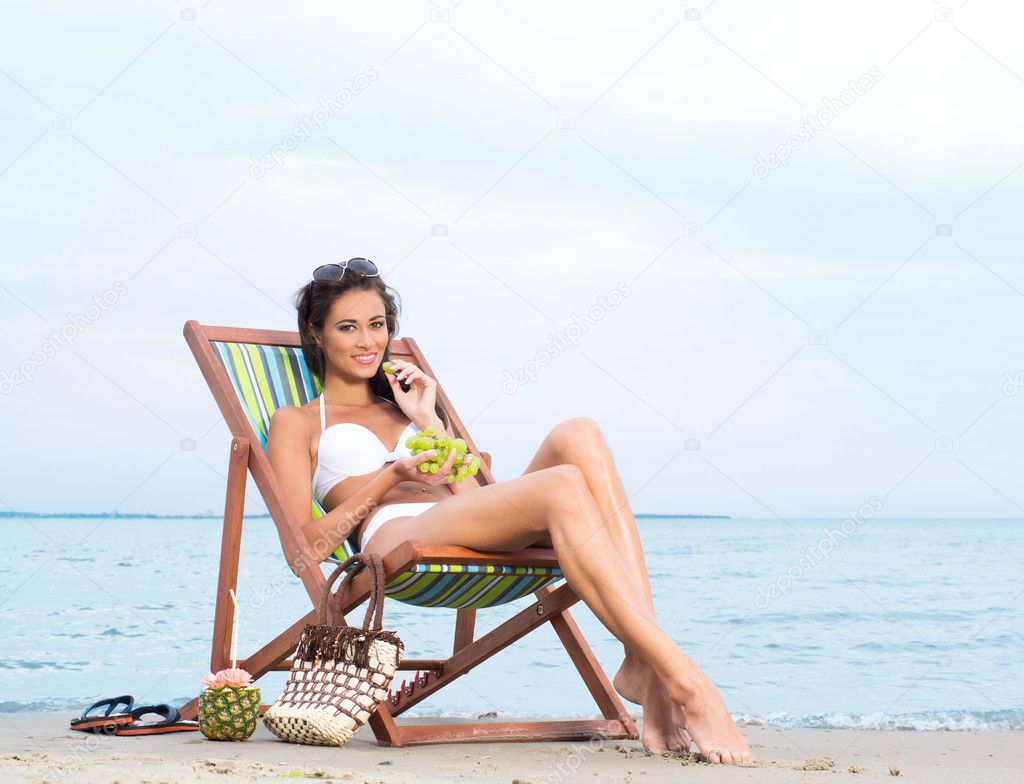 sexy woman eating grapes on the beach
