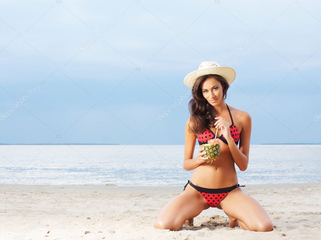 beautiful and sexy woman drinking exotic cocktail on the beach