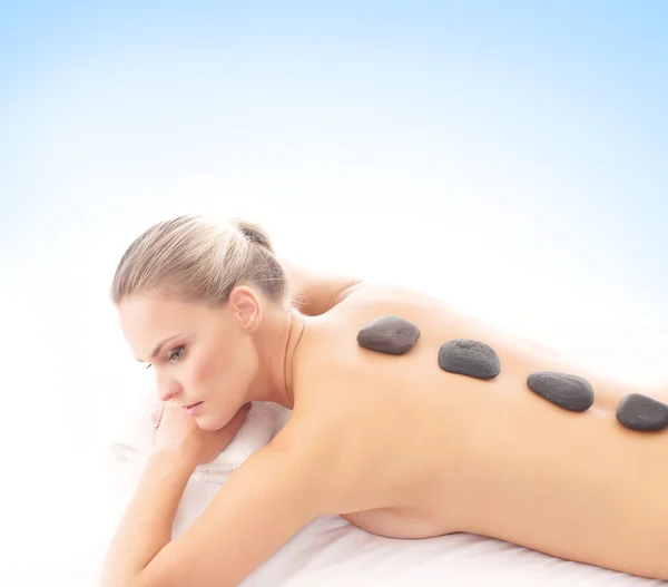 Young attractive woman getting hot stone treatment over white ba — Stock Photo, Image